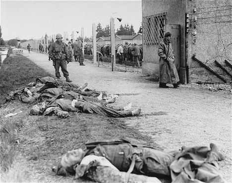 An American soldier stands beside the bodies of SS personnel shot by U.S. troops